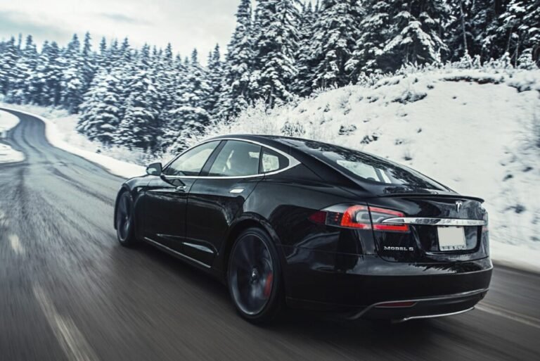 Une Tesla roule sur une route en forêt en plein hiver