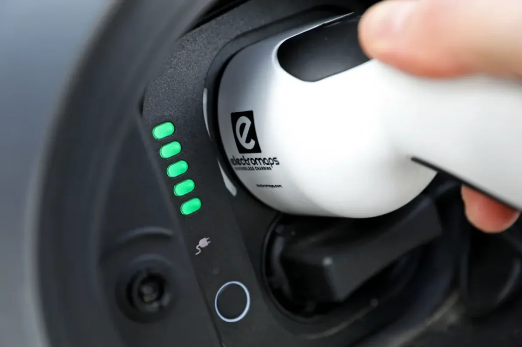 Visuel représentant une main qui branche une prise sur un véhicule électrique
